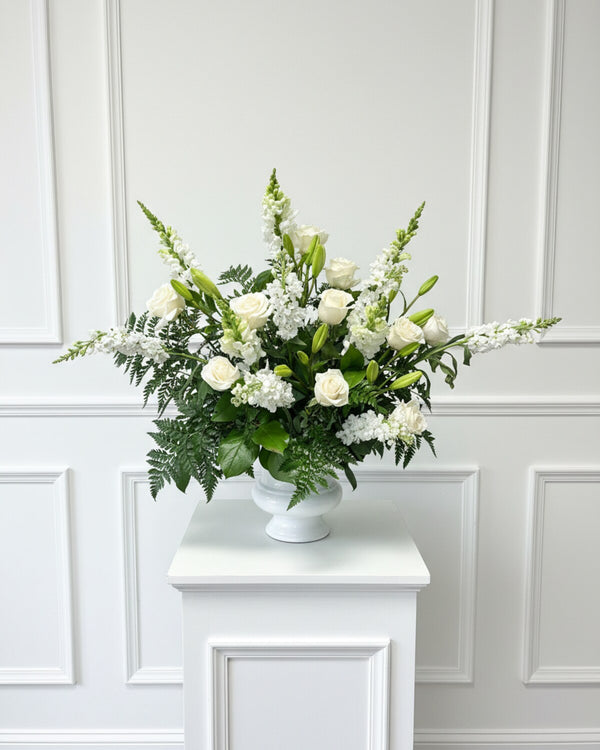 White Pedestal Urn — a pedestal urn arrangement of white roses, lilies, and hydrangea, elegant and serene