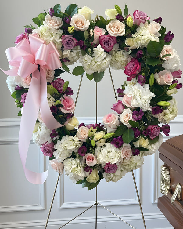 Pink Heart Wreath — heart-shaped standing wreath of pink and lavender roses and white hydrangea with a pink bow