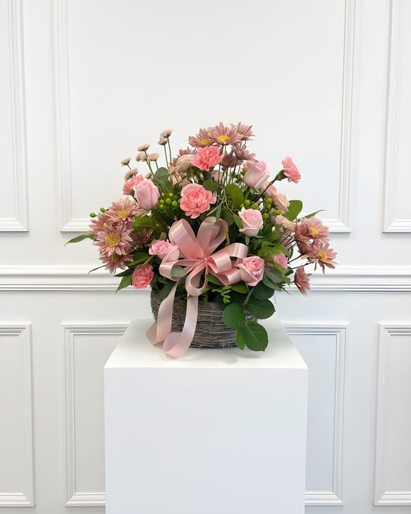 Pink Basket — woven basket of pink roses and dusty-rose daisy mums with a pink bow