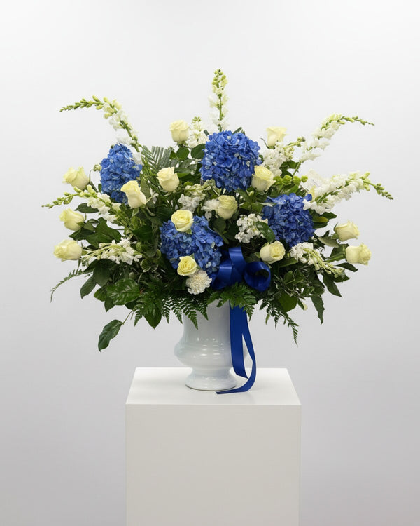Cornflower Blue Urn — blue hydrangea with white roses and white snapdragons in a white pedestal urn