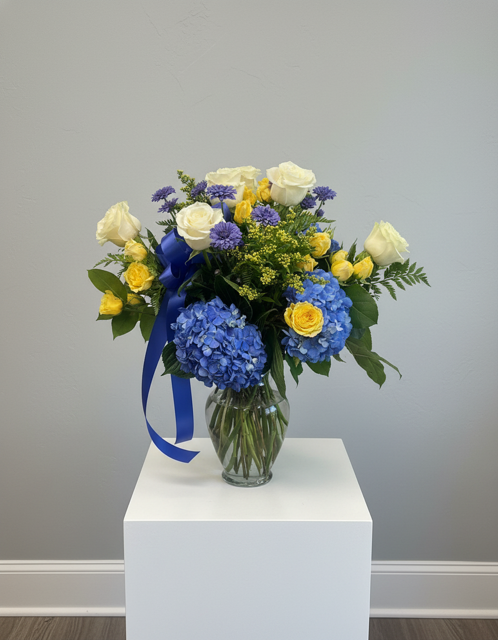 New Blue Arrival: blue hydrangea, white and yellow roses and a blue ribbon in a glass vase