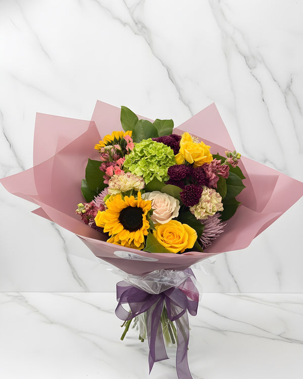 Sunflower Wrap — a bouquet of bright sunflowers paired with seasonal greenery and a pop of yellow solidago