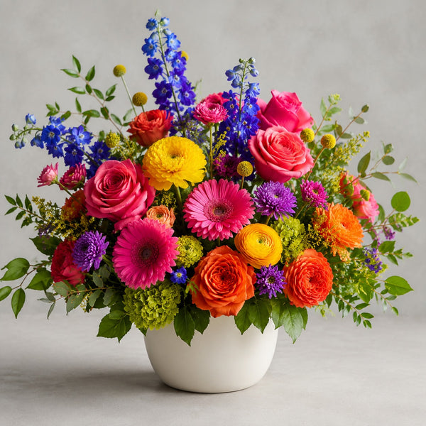 Designer's Choice - Bright Mixed Colors — florist's-choice arrangement in bold pinks, oranges and yellows with pops of blue and purple, shown in our ceramic vase