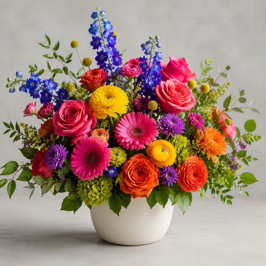 Designer's Choice - Bright Mixed Colors — florist's-choice arrangement in bold pinks, oranges and yellows with pops of blue and purple, shown in our ceramic vase