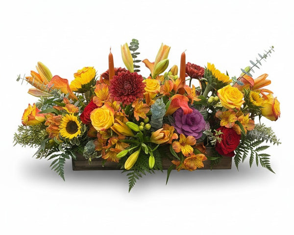 Harvest Centerpiece — low wooden box of sunflowers, roses, orange lilies, burgundy mums and purple kale with two taper candles